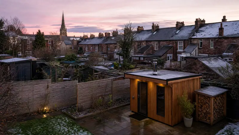 Wood-fired garden sauna behind a row of terraced houses in a town